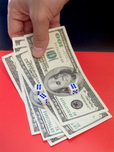 A hand holding dollar bills with dices on top of it