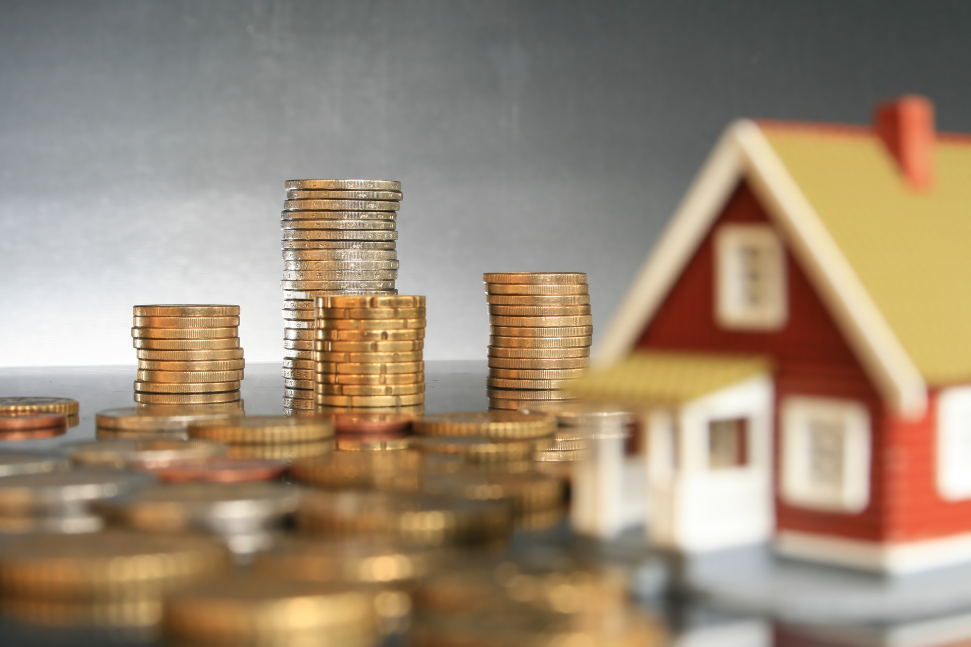 A stack of coins and a house model