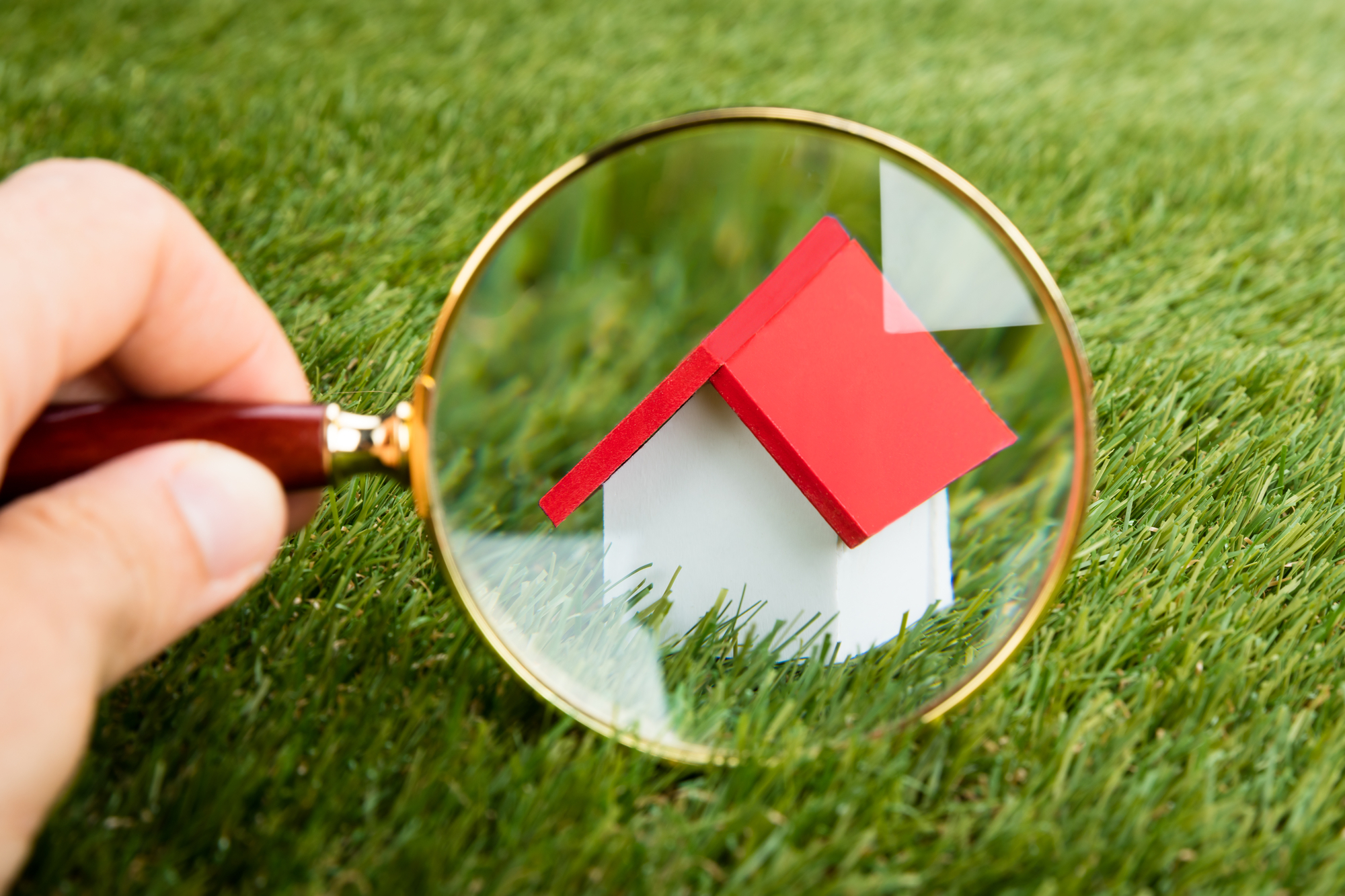 House model being looked at through a magnifying glass