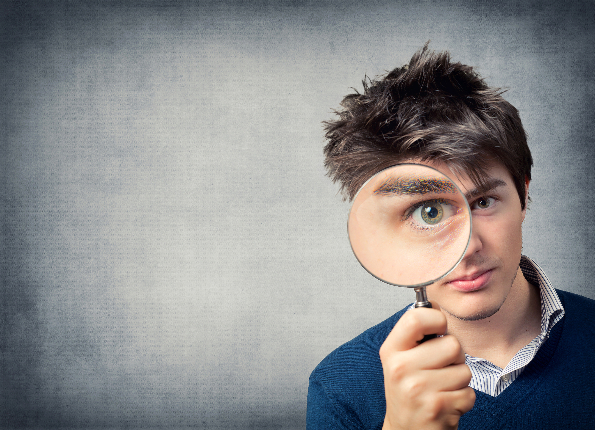 A man holding a magnifying glass in front of his face