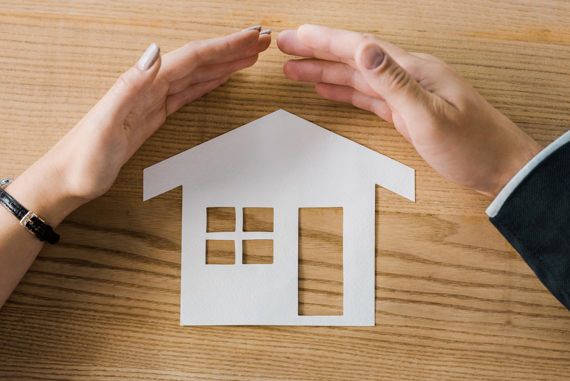 cutout of a house with a pair of hands over it