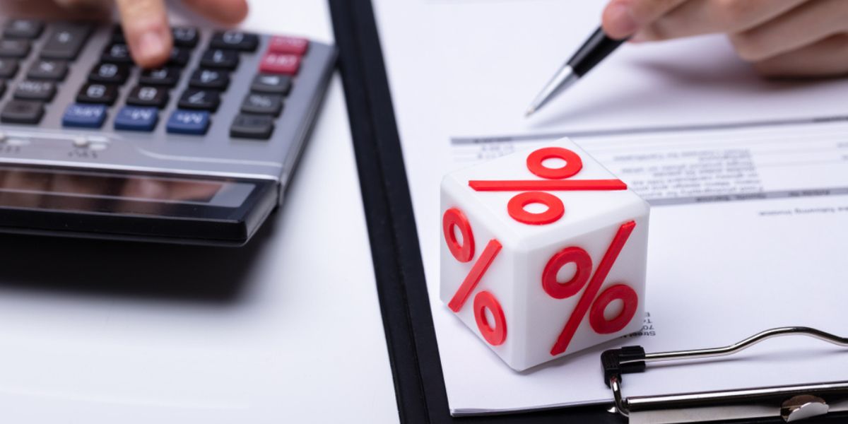 Close-up Of White Block With Percentage Symbol While Businessperson Calculating Invoice Over White Desk