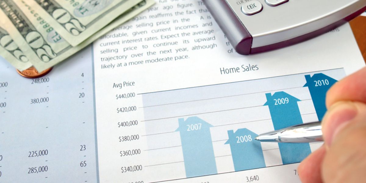 Male hand with pen on the investment chart with calculator and dollars