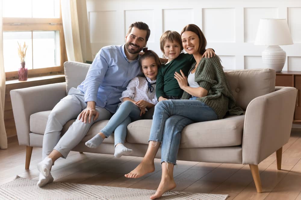 happy young family with two small kids relaxing on a couch