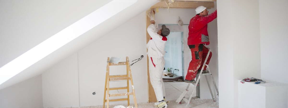 Construction worker is painting the wall in new house