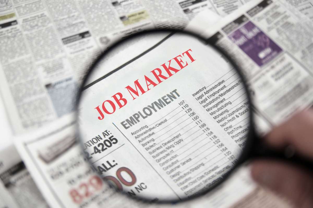 Magnifying glass on the newspaper magnifying the words job market