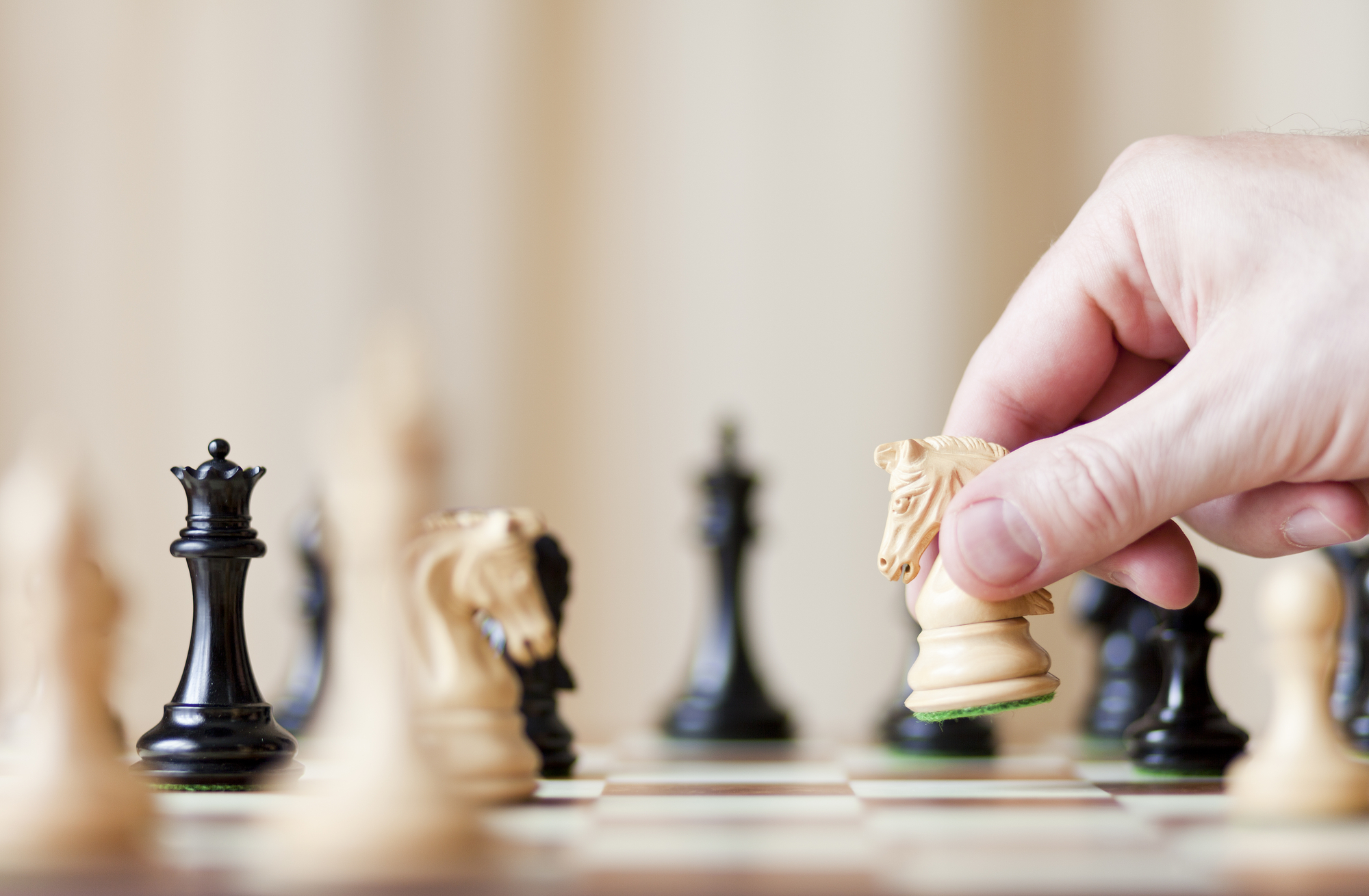 hand holding a chess piece over a chessboard